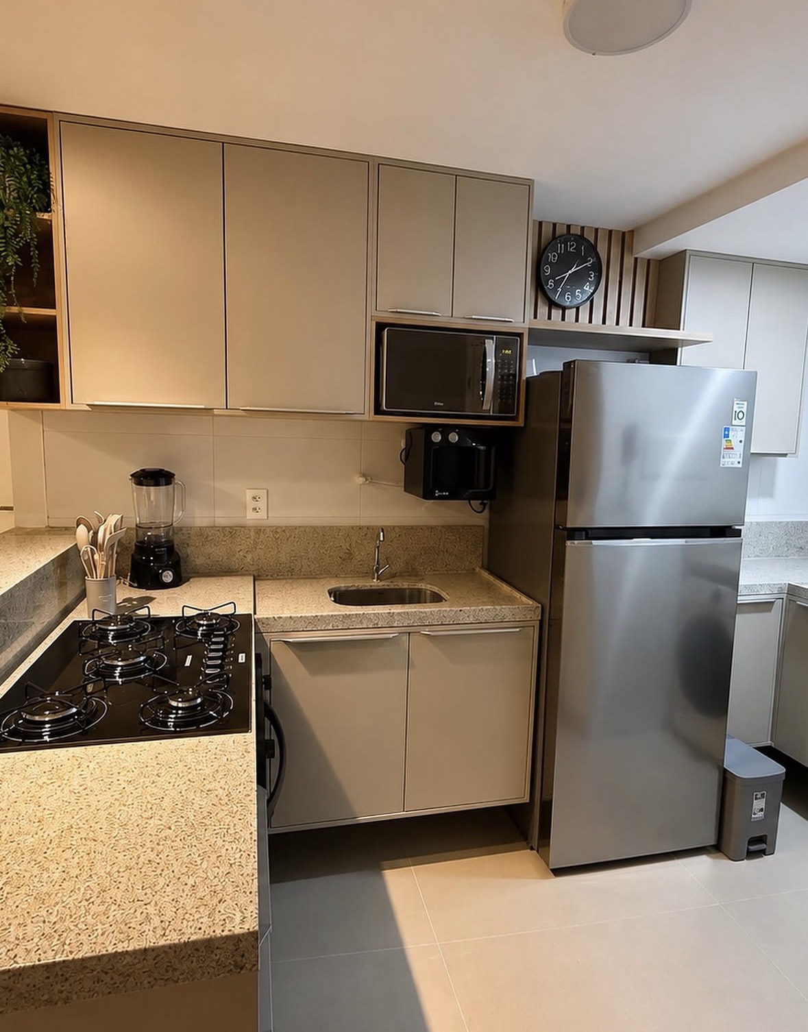 Cozinha em L com armários claros, nicho para micro-ondas e detalhe ripado
